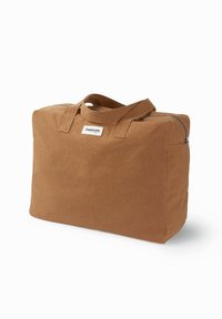 Sac de voyage en tissu brun de forme rectangulaire, fermeture éclair, deux poignées supérieures et une étiquette sur le devant. Texture douce.