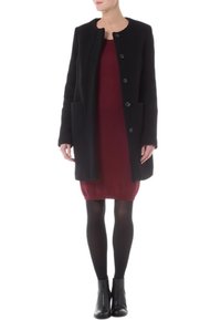 Cappotto in misto lana nero con scollo rotondo, cinque bottoni e tasche laterali, indossato sopra un vestito bordeaux, abbinato a stivaletti neri alla caviglia.