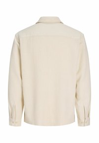 Chemise beige texturée à manches longues avec poignets boutonnés, vue de dos sur fond blanc.