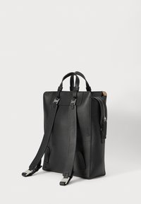 Zaino nero in pelle con spallacci regolabili, accessori in argento, tasca con cerniera e forma rettangolare strutturata. Texture liscia.