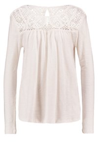 Långärmad blus i ljus cream med en texturerad spets yoke och nyckelhål baktill. Löst sittande med rynkdetaljer under yoken.