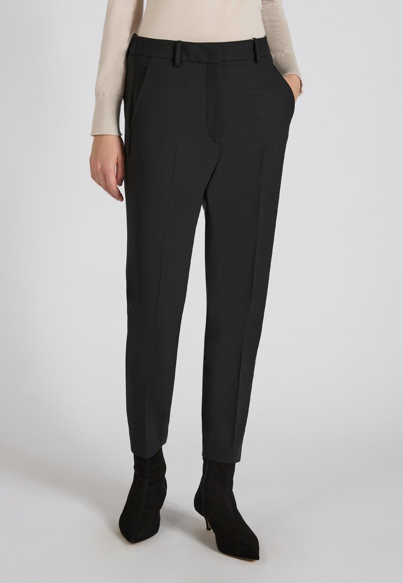 Czarne spodni o dopasowanym kroju z gładką fakturą, z bocznymi kieszeniami i slim fit. Połączone z czarnymi, spiczastymi botkami za kostkę.