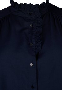 Blusa de un azul marino oscuro con un alto cuello rizado, tapeta frontal con botones negros redondos y una tela suave y texturizada.