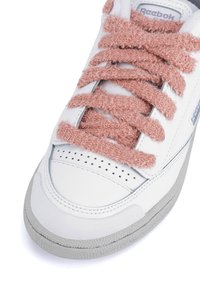 Adidași albi cu șireturi din bumbac moale roz, detalii perforate pe vârf și o talpă din cauciuc gri. Prezintă branding Reebok pe lateral.