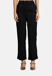 Zwarte textuur hoge taille wijde pijpen broek gedragen met glanzende metallic puntige hakken met versierde banden.
