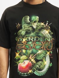 Černé bavlněné tričko s barevným grafickým designem znázorňujícím hada, jablko, listy a nápis "ZAHRADA EDENU" ve zdobném zlatém písmu.