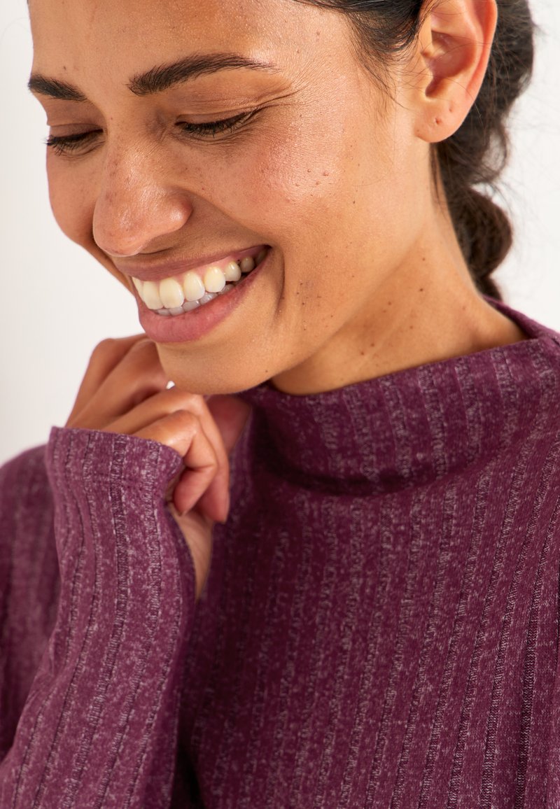 Violetter, gerippter Rollkragenpullover mit langen Ärmeln, der aus einem strukturierten Stoff gefertigt ist. Der Kragen ist hoch und enganliegend.