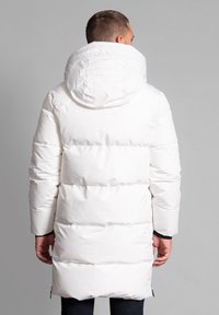 Witte pufferjas met een grote capuchon, voorzien van quilted panelen en een gladde, glanzende afwerking. Ritsen bij de mouwen en aan de zijkanten.