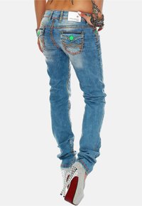 Jeans skinny in denim blu chiaro, con cuciture dettagliate, due tasche posteriori con decorazioni e una vita media.