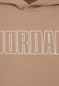 Beige Kapuzenpullover mit einem strukturierten geometrischen Muster und großen weißen "JORDAN"-Buchstaben über der Brust. Hergestellt aus weichem Stoff.