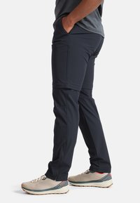 Pantaloni da uomo navy elasticizzati con tasche con cerniera, vestibilità affusolata e polsini regolabili. Il materiale sembra leggero e resistente, adatto per uso all'aperto.