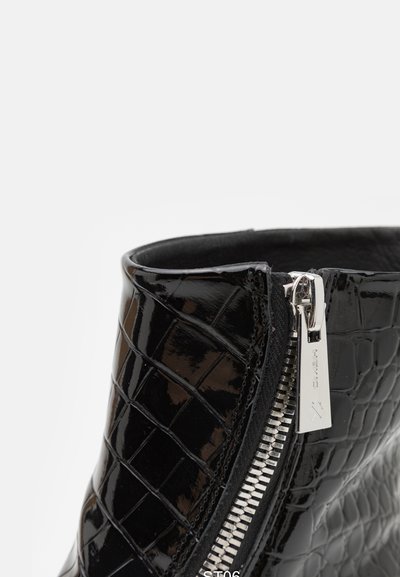 Black patent leather ankle boot with crocodile texture. Features a side zipper with silver hardware and a smooth interior finish.
