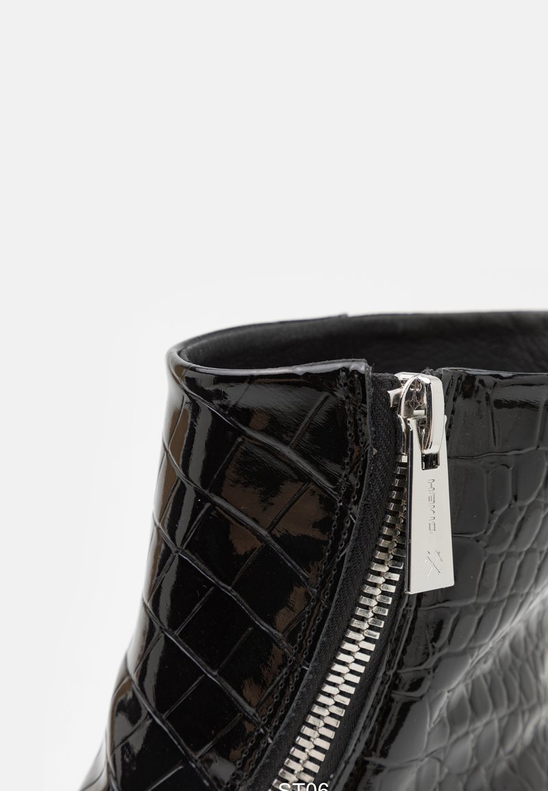 Zwarte gepatineerde leren enkellaars met krokodillenstructuur. Voorzien van een zijrits met zilveren hardware en een gladde binnenafwerking.