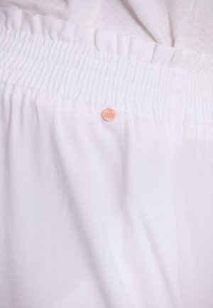 Weißer Stoff mit texturiertem Gummibund. Verfügt über ein kleines, rundes Markenschild in einem hellen Pfirsichton. Der Stoff hat eine glatte, weiche Textur.