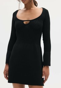 Czarna sukienka prążkowana z okrągłym dekoltem i małym wycięciem w kształcie klucza. Długie rękawy i dopasowany gorset przechodzący w rozkloszowany dół.