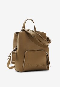 Bruine leren emmerzak met een gevlochten handvat, voorzak met rits en een gegraveerd logo. Textuur oppervlak en verstelbare schouderriem inbegrepen.