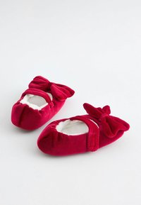 Pantofole da balletto in velluto rosso con un morbido rivestimento interno, caratterizzate da un grande fiocco su ciascuna scarpa e una fascia elastica per una vestibilità sicura.