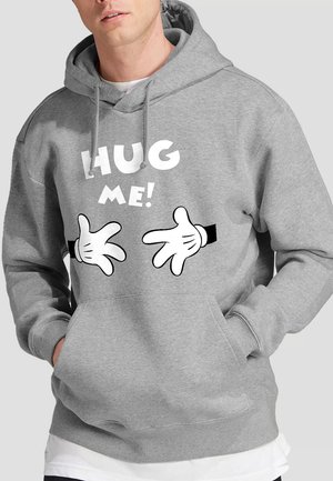 Gray hoodie with a front pocket, featuring "HUG ME!" text and cartoon-style hands. Soft fabric with drawstrings at the hood.