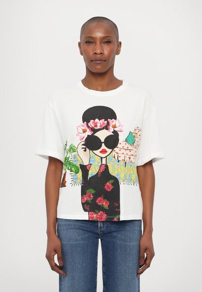 Hvit bomulls T-skjorte med et fargerikt grafisk design av en kvinne med solbriller, med blomsterdetaljer på en svart bakgrunn.