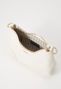 White leather bag with embossed floral pattern, gold zipper, circular hardware, and lined interior featuring horizontal stripes and a pocket.
