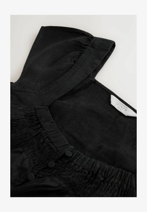 Čierny ľanový top s nariasenou textúrou pozdĺž výstrihu, zdobený gombíkmi a so skladaným golierom. Tkanina je hladká a ľahká.