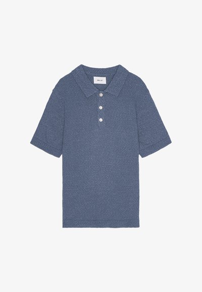 Sininen neulepolo, jossa on lyhyet hihat, kauluskaitale, kolme nappia ja teksturoitu pinta.