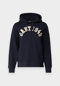 Sweat-shirt à capuche bleu marine en tissu doux. Il présente une poche kangourou, des poignets côtelés et une broderie contrastante "GANT 1949" sur la poitrine.