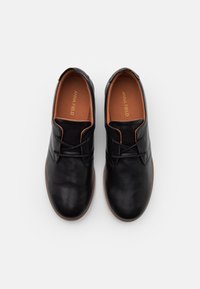 Scarpe nere in pelle con una texture liscia, forma arrotondata e dettagli marroni. Hanno una chiusura con lacci e una morbida fodera interna.