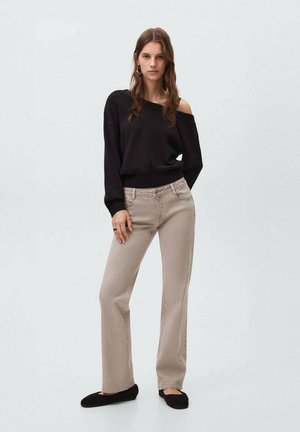 Svart off-shoulder tröja med ribbat nederkant, ihop med ljusbeiga raka jeans med sidostygn och svarta sneakers.
