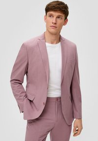 Helle rosa Anzugjacke mit einem einreihigen Blazer, Reverskragen und zwei Knöpfen. Kombiniert mit passenden Hosen und einem weißen T-Shirt darunter.