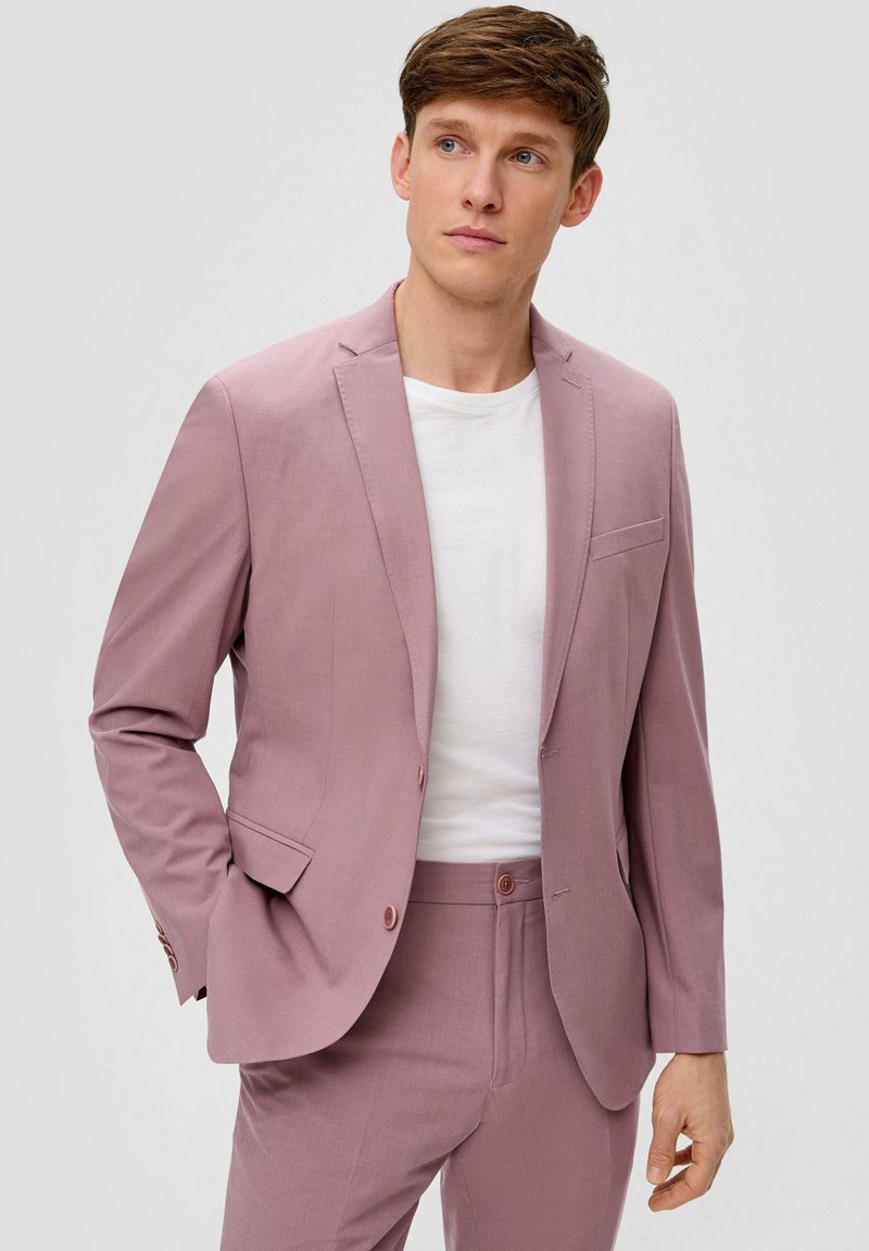 Helle rosa Anzugjacke mit einem einreihigen Blazer, Reverskragen und zwei Knöpfen. Kombiniert mit passenden Hosen und einem weißen T-Shirt darunter.
