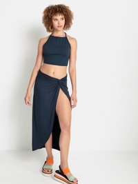 Haut court halter bleu marine associé à une jupe maxi nouée avec une fente sur la jambe. Le modèle porte des sandales à semelles épaisses multicolores.