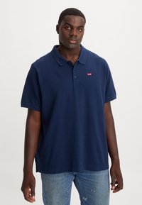 Polo azul-marinho em algodão, com gola canelada, mangas curtas e um pequeno logótipo vermelho da Levi's no peito esquerdo.
