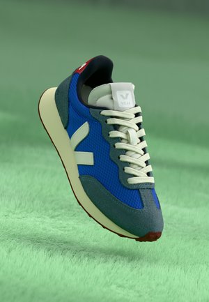 Niebieskie i szare buty sportowe z siateczkowym materiałem, zamszowymi akcentami, białymi sznurowadłami i czerwoną metką. Posiadają gumową podeszwę i wyraźne logo.