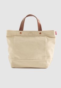 Beige canvas schoudertas met bruine leren handvatten en een klein rood Levi's-label aan de rechterkant, tegen een effen lichte achtergrond.
