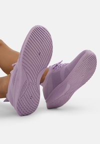 Scarpe da ginnastica viola con suole testurizzate, tomaia in mesh traspirante e dettagli del laccio. Punta arrotondata e design della suola flessibile.