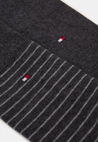 Donkergrijze sokken met een effen gedeelte en een gestreept patroon. Logo in rood, wit en blauw. Zachte textuur, halflange lengte.