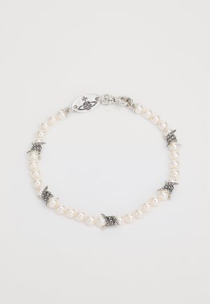 Bracelet en perles avec accents en argent, présentant de petits éléments décoratifs et une fermeture à clip. Texture lisse et forme ronde uniforme.
