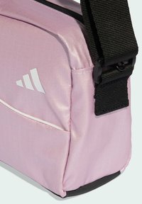 Pink synthetic shoulder bag with a smooth texture, featuring a white logo and a black adjustable strap. Includes a contrasting trim.