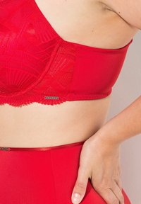 Red bra and high-waisted brief set, featuring textured lace overlays, smooth fabric, and decorative logo detail on the waistband.