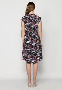 Rochie florală cu fundal negru, având modele roșii, albastre și albe. Mâneci scurte și talie ajustată, terminându-se la lungimea genunchiului.