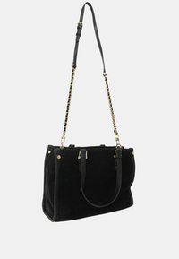 Borsa tote in velluto nero con forma strutturata. Presenta manici in pelle e un accento in catena dorata. Include finiture dorate e chiusure laterali con zip.
