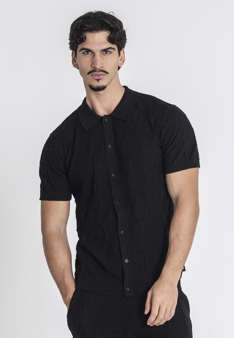 Zwart polo shirt met korte mouwen, voorzien van een gestructureerd ruitpatroon, knoopsluiting en ribgebreide kraag en zoom. Gemaakt van zachte stof.