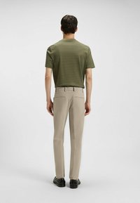 Olijfgroene gestructureerde t-shirt voor heren, slim fit, gecombineerd met beige recht gesneden broeken. Zwarte schoenen maken de outfit compleet.