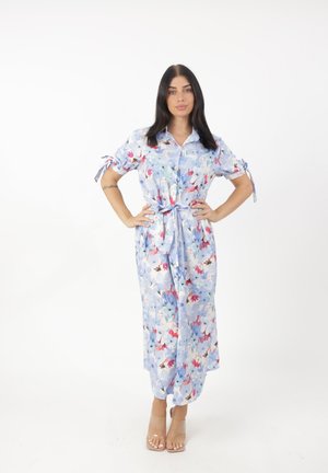 Robe maxi fleurie en tissu bleu clair, avec des manches courtes, un devant à boutons et un détail de taille nouée. Agrémentée de motifs floraux colorés.