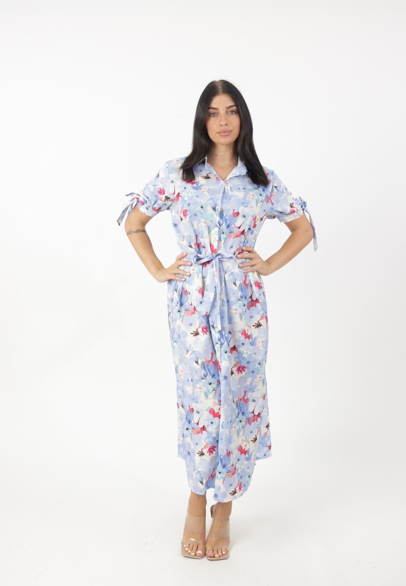 Floral maxi-jurk in lichtblauwe stof, met korte mouwen, een knoopsluiting aan de voorkant en een strikdetail bij de taille. Versierd met kleurrijke bloemenpatronen.
