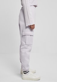 Jasnofioletowe spodnie cargo wykonane z miękkiego materiału, z boczną kieszenią, elastycznym pasem i mankietami. W komplecie z białymi sneakersami.