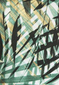 Des formes et lignes angulaires vertes, beiges et noires se chevauchant, créant un motif géométrique abstrait sur un tissu.