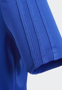 Blaues sportliches T-Shirt mit drei vertikalen Streifen; glatte Textur, taillierte Passform und Kontrastnaht am Saum.