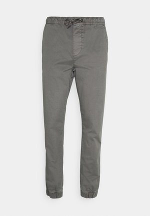 Pantalons grijs légers avec une taille élastique et un cordon de serrage. Design fuselé avec des poignets élastiques aux chevilles. Texture lisse.